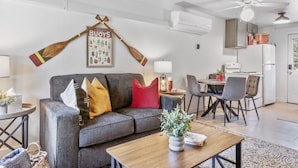 Una sala de estar con un sofá gris, una mesa de centro de madera y un comedor con mesa y sillas.