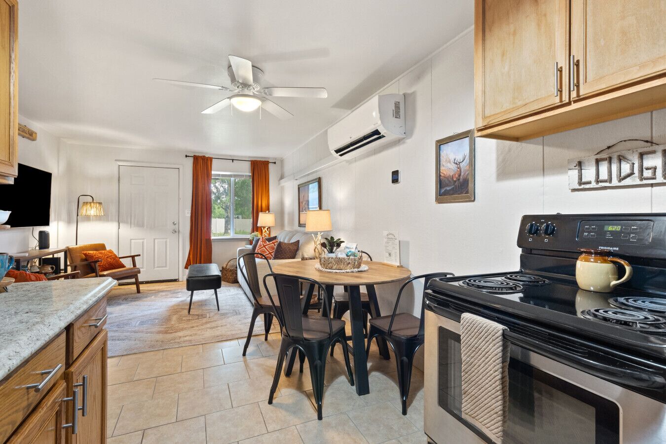 A kitchen with a stove, dining table, chairs, and a ceiling fan.