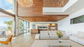 Sala de estar moderna com sofá, mesa de centro e vista para a cozinha.