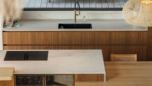 Uma cozinha moderna com bancada de madeira, espaço para vinhos embutido e área de refeições com mesa e cadeiras de madeira.
