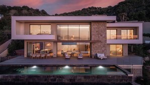 A modern two-story house with a swimming pool, large windows, and a stone pillar. - Villa MAAMI (Pietrosella)