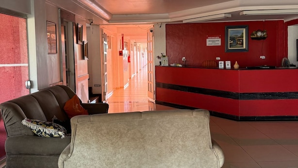 Un hall d’hôtel comprenant un comptoir d’accueil, un canapé et un couloir menant à d’autres chambres.