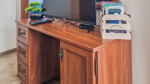 A wooden entertainment center with a flat-screen TV, a remote control, and a small potted plant. There are books on the right side of the TV. - Charming 1-bedroom hotel suites in wonderful Bansko with WiFi (Bansko)