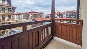 A balcony with a wooden railing overlooking a row of buildings with red roofs. - Charming 1-bedroom hotel suites in wonderful Bansko with WiFi (Bansko)
