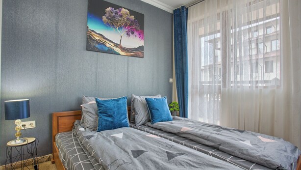A bedroom with a bed, a nightstand, a lamp, and a painting on the wall. - Charming 1-bedroom hotel suites in wonderful Bansko with WiFi (Bansko)