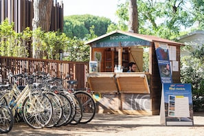 Un kiosque d’information en bois, avec une pancarte indiquant « POINT INFO » et une personne à l’intérieur.