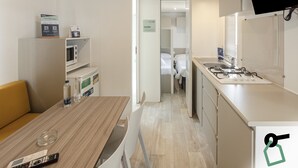 A compact hotel room with a kitchenette, a dining area, and a bed. - Hotiday Lodge Orbetello (Orbetello)
