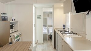 A compact hotel room with a kitchenette, a dining area, and a bed. - Hotiday Lodge Orbetello (Orbetello)