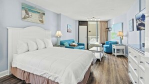 Ein Schlafzimmer mit einem großen Bett, zwei blauen Sesseln, einem kleinen Tisch und einer Kommode.