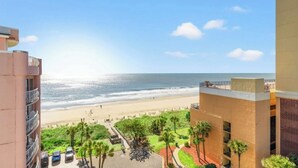 Ein Hotel direkt am Strand mit Blick auf den Ozean, einem Parkplatz und einem angelegten Garten.