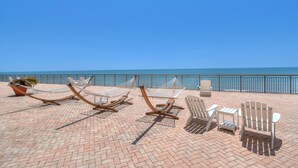 Eine Terrasse direkt am Strand mit Hängematten, Adirondack-Stühlen und einem kleinen Tisch.