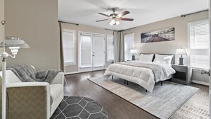 A bedroom with a bed, a chair, a ceiling fan, and a window with blinds. - Stylish & Modern Private Getaway in Richardson! (Richardson)