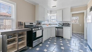 A kitchen with white cabinets, a stainless steel stove, and a tiled floor. - Stylish & Modern Private Getaway in Richardson! (Richardson)
