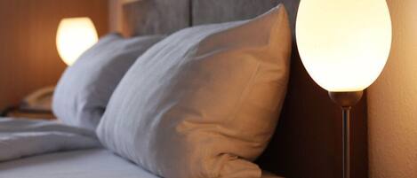 A neatly made bed with pillows and a bedside lamp.