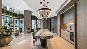 Una cocina moderna con una isla de mármol, iluminación colgante y vistas a la ciudad.