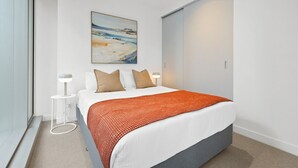 Ein modernes Schlafzimmer mit Bett, Gemälde und Kleiderschrank.