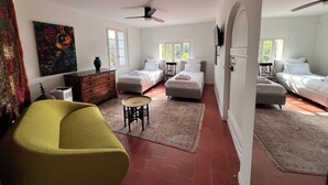 Una camera spaziosa con due letti, un divano, un tavolino e una ventola a soffitto.