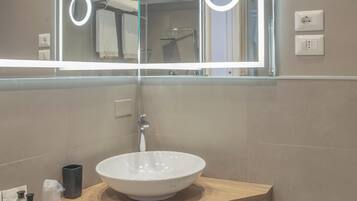 Un baño moderno con un espejo grande, un lavabo blanco y una encimera de madera.