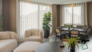 A modern living room with a sofa, a dining table, and a large potted plant. - Hotiday Mondello Beach (Palermo)