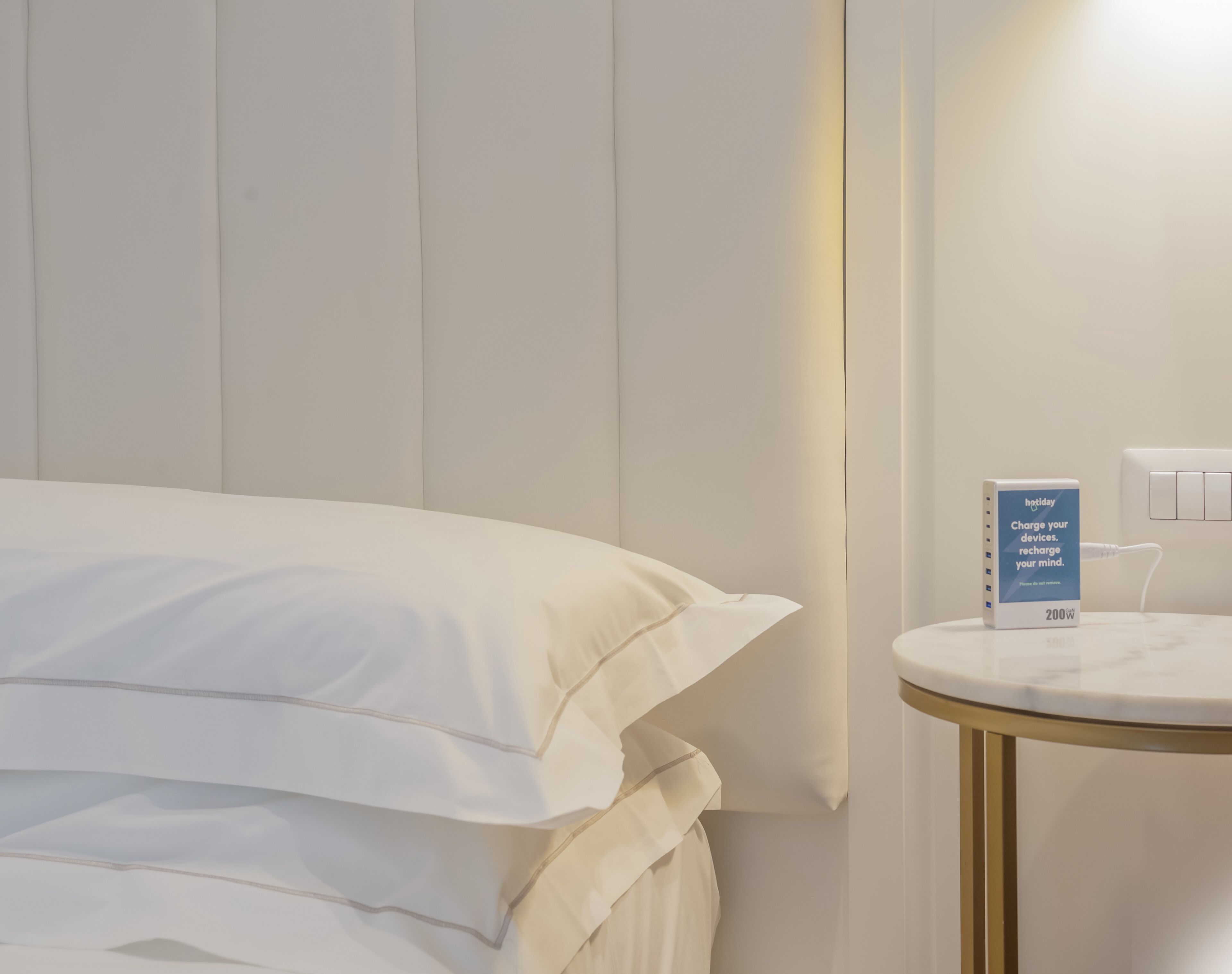 Een hotelkamer met een bed, een nachtkastje met een powerbank en een stopcontact.