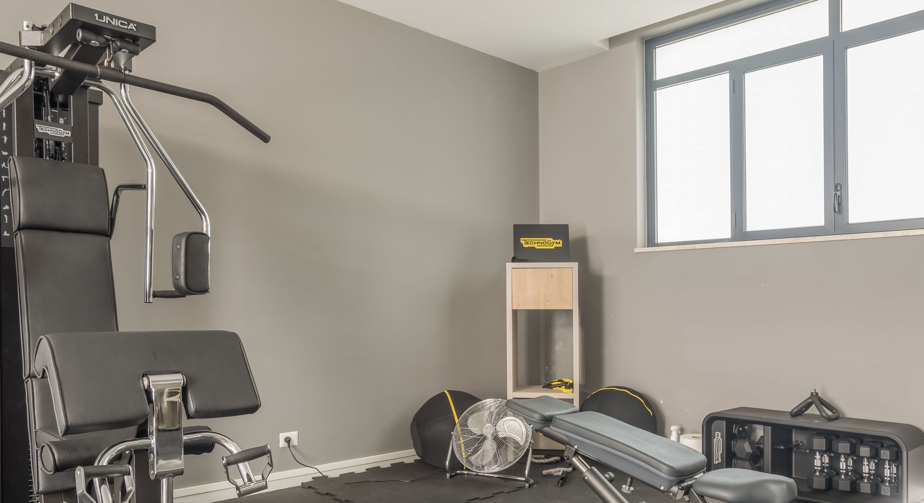 A home gym with a pull-up bar, exercise bench, and weight rack.