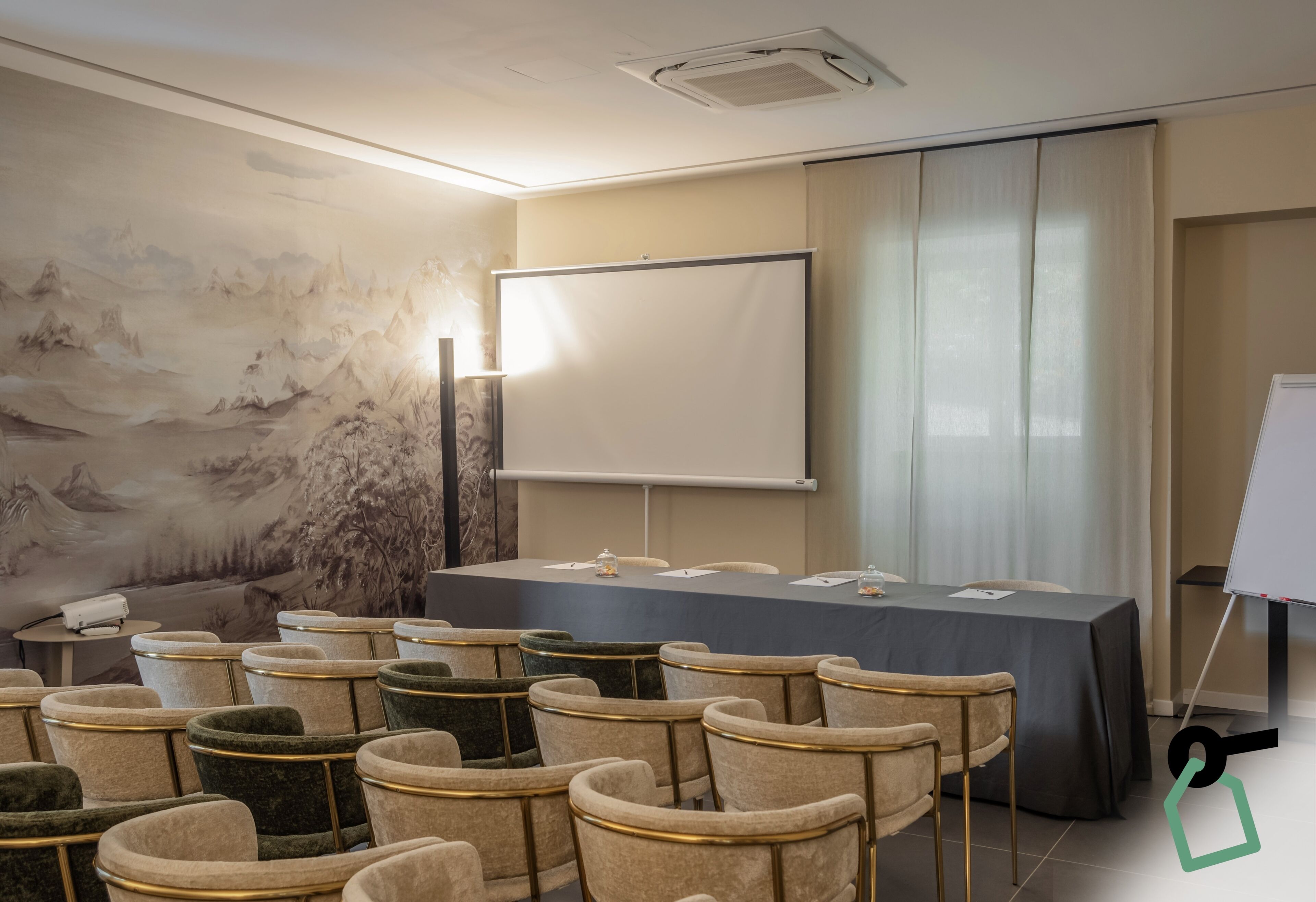 A conference room with a long table, chairs, a projector screen, and a painting on the wall.