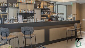 A bar area with shelves of bottles, a counter, and seating. - Hotiday Mondello Beach (Palermo)