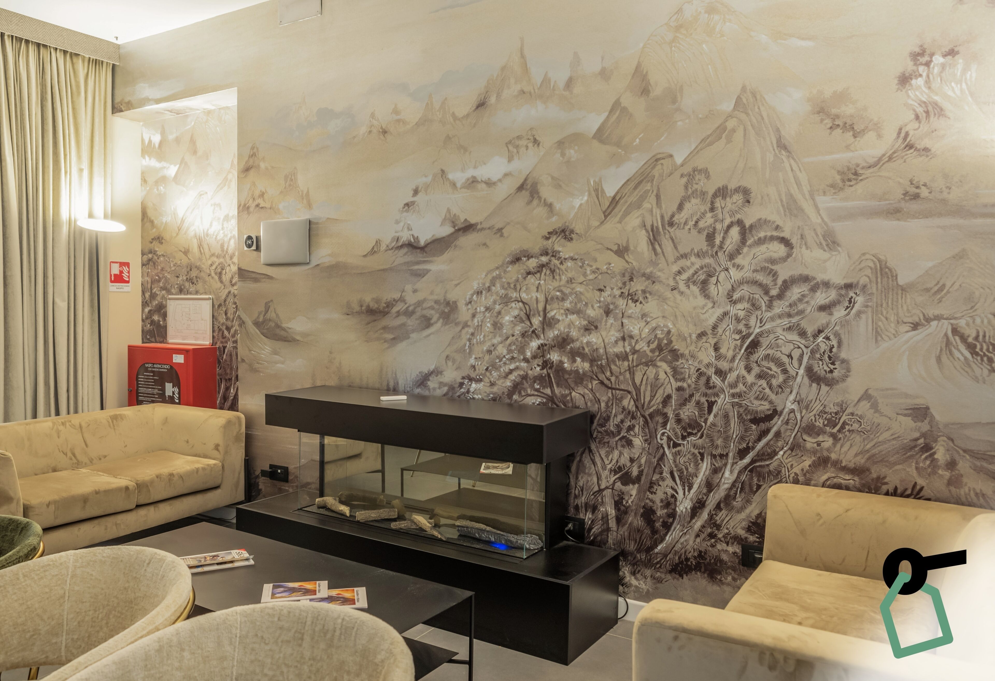 A room with a large wall mural, a fish tank, and two sofas.