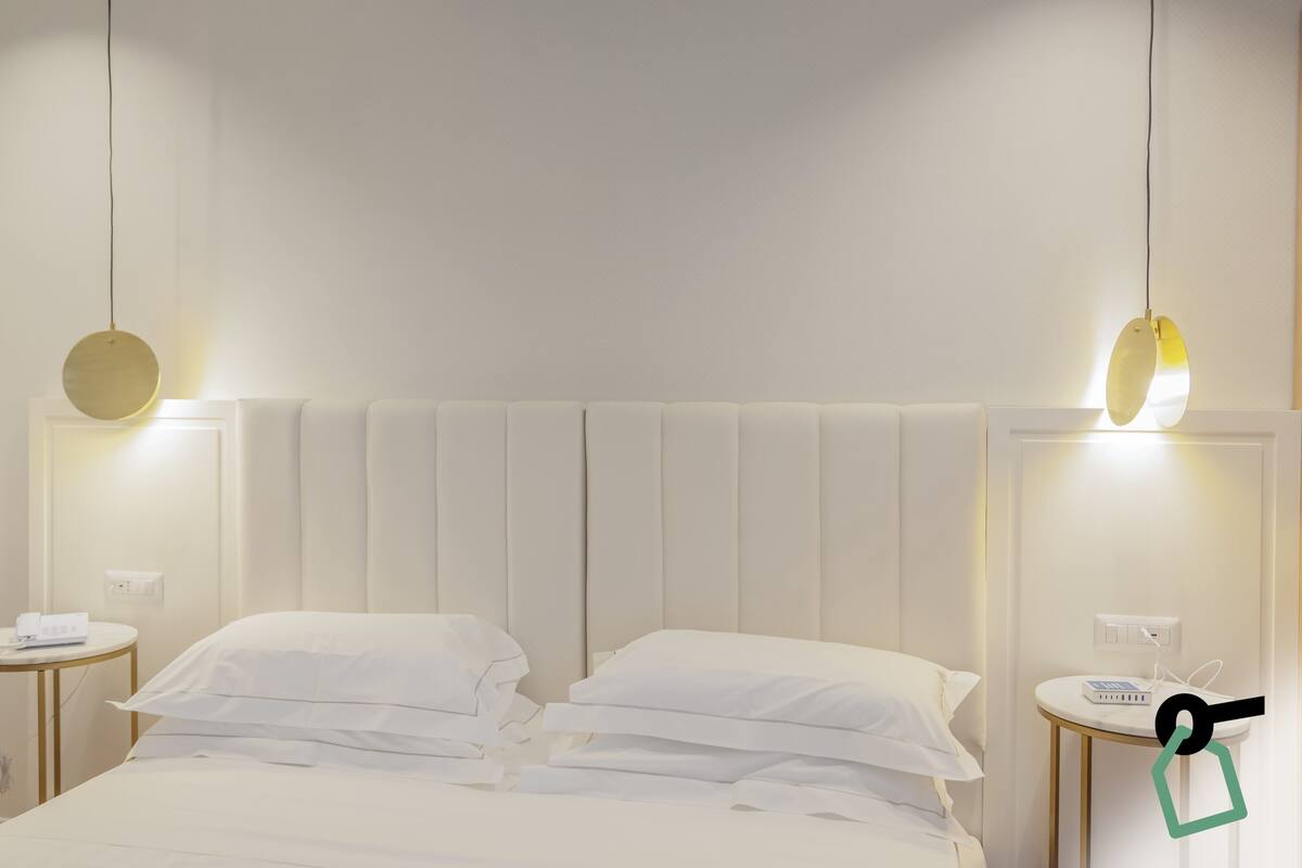 Une chambre d’hôtel avec un lit, des tables de chevet et un luminaire fixé au mur.