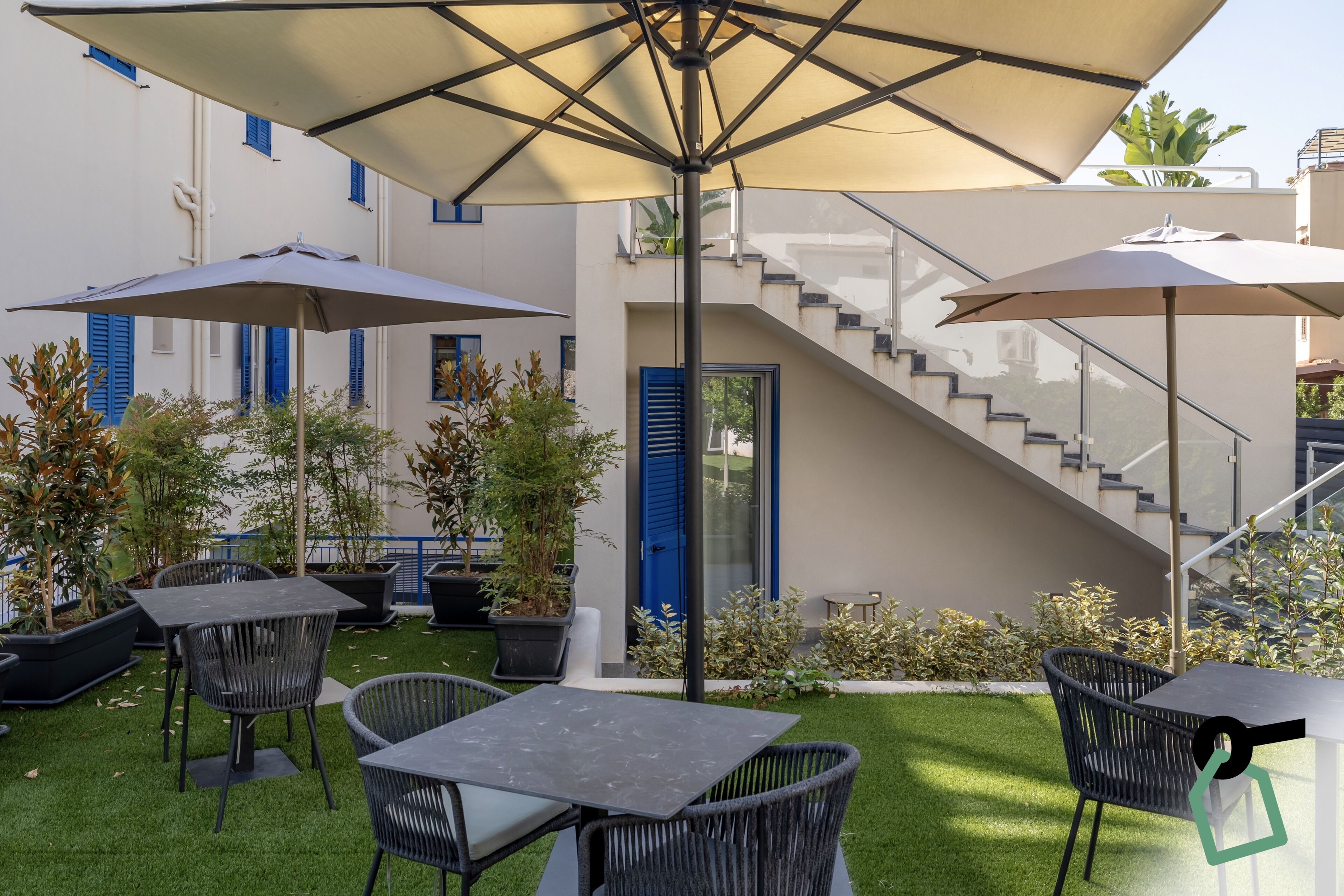 Ein Innenhof mit Außenplätzen, einer Treppe und Kübelpflanzen.