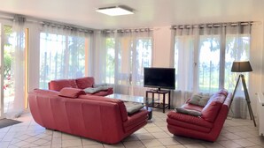 A living room with a red sofa set, a flat-screen TV, and a floor lamp. - Gîte des Orgues d'Ille Eucalyptus (Ille-sur-Têt)