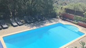 A rectangular swimming pool with a tiled edge, surrounded by lounge chairs and a stone deck. - Gîte des Orgues d'Ille Eucalyptus (Ille-sur-Têt)