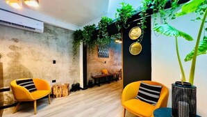 A modern interior with two yellow armchairs, a bench, and a large potted plant. - Private 3 floors building 8 bedrooms 10 bathrooms for 30 people, Best Location (Playa del Carmen)