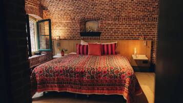 A bedroom with a brick-patterned ceiling, a bed with a floral-patterned bedspread, a wooden headboard, and a nightstand with a lamp.