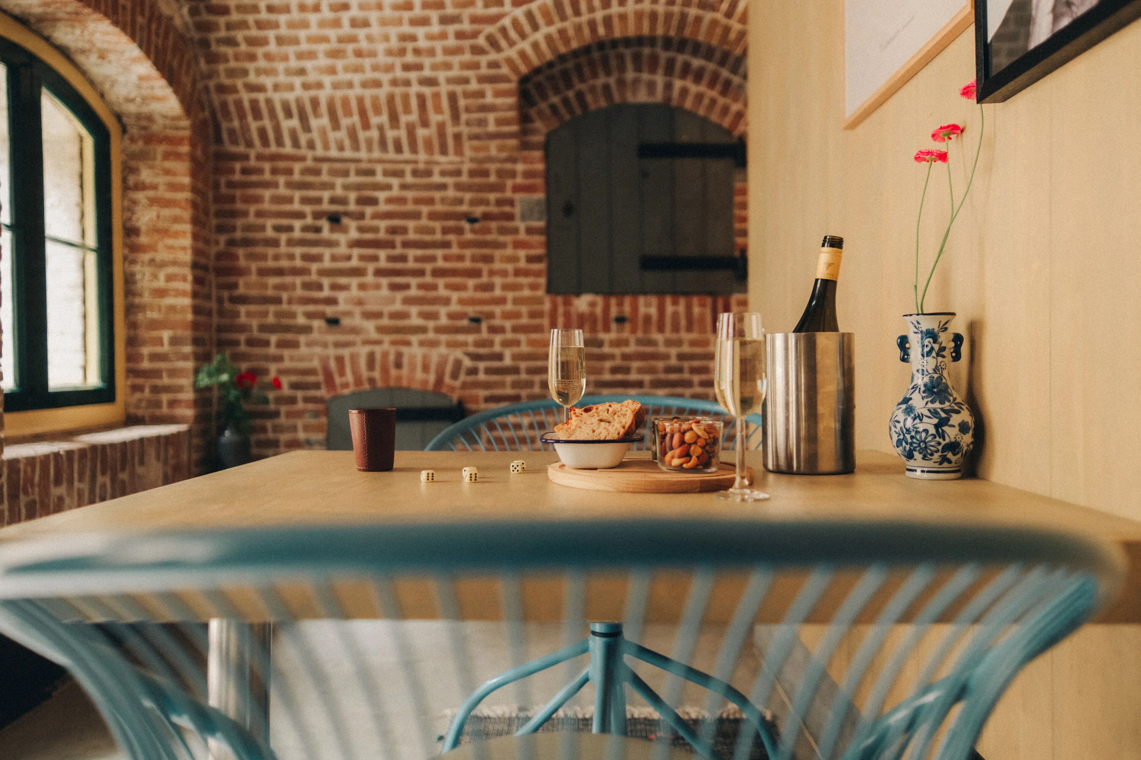 Een eettafel met een schaal noten, een fles wijn en glazen.