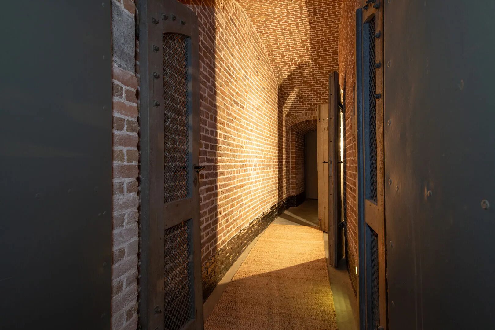 A narrow brick corridor with a carpeted floor and a blue door on the right.