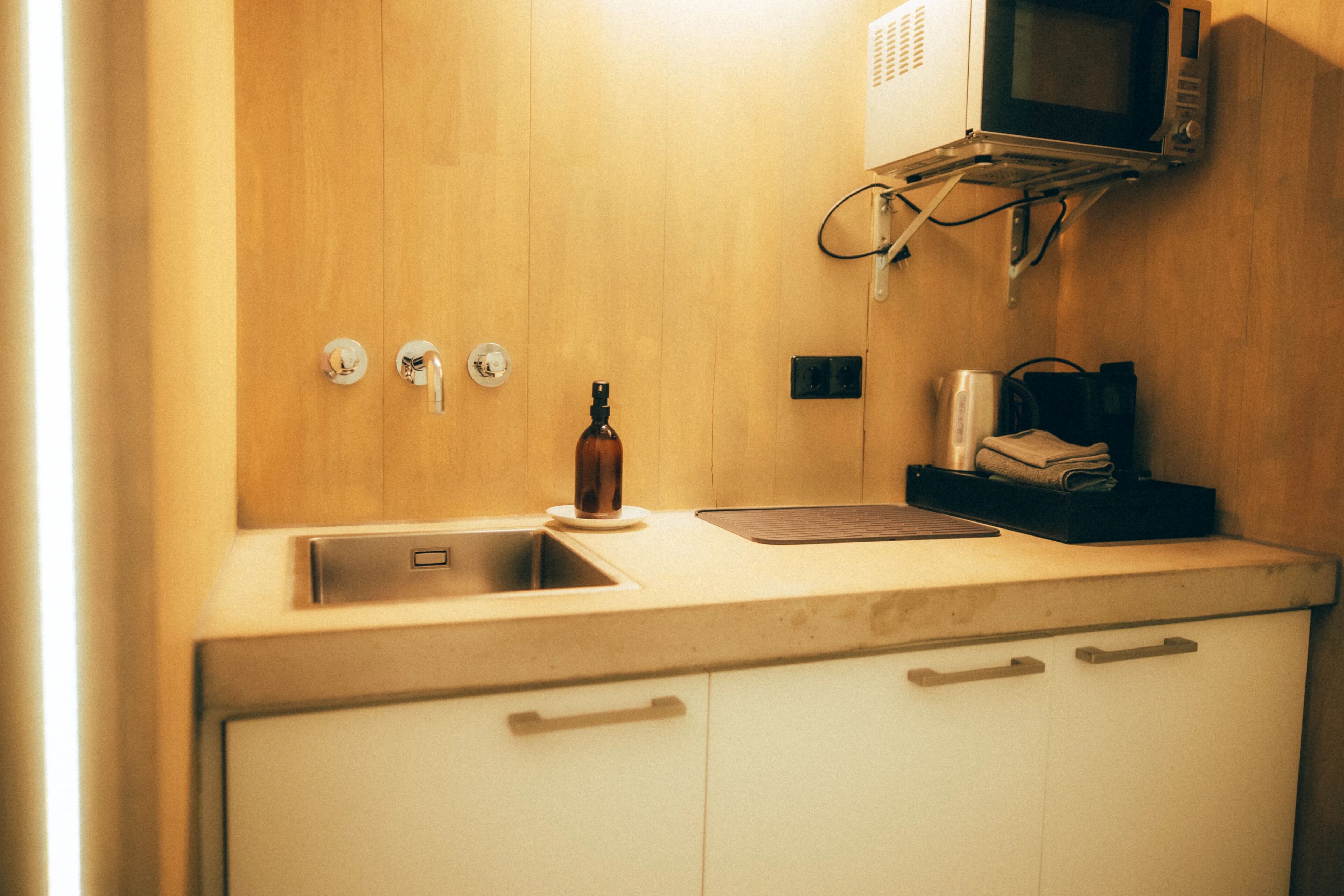 Una cocina con encimera de madera, un fregadero, microondas y cafetera.