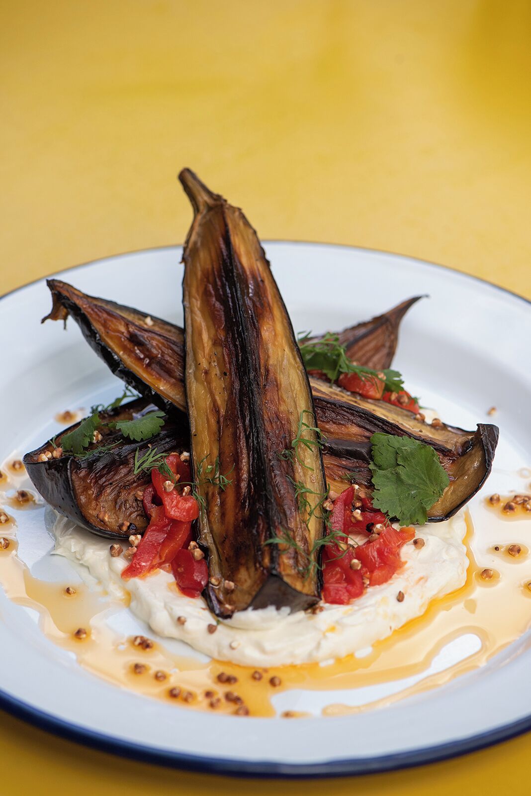 Un plato de berenjena asada con salsa cremosa y guarniciones.