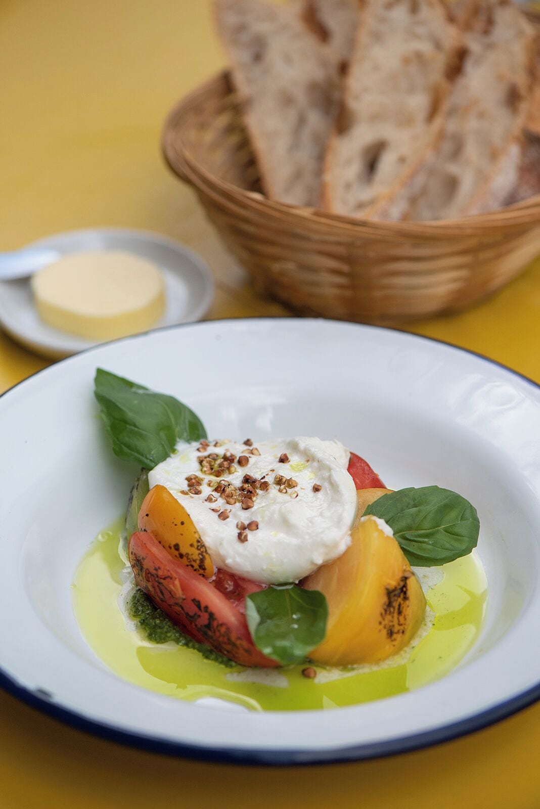 A plate of food with a poached egg, tomatoes, basil, and olive oil.