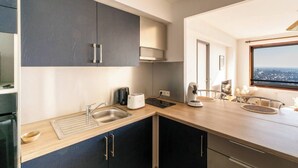 A modern kitchen with dark cabinets, a stainless steel sink, a toaster, and a coffee maker. - Breathtaking view - Private garage (Rennes)