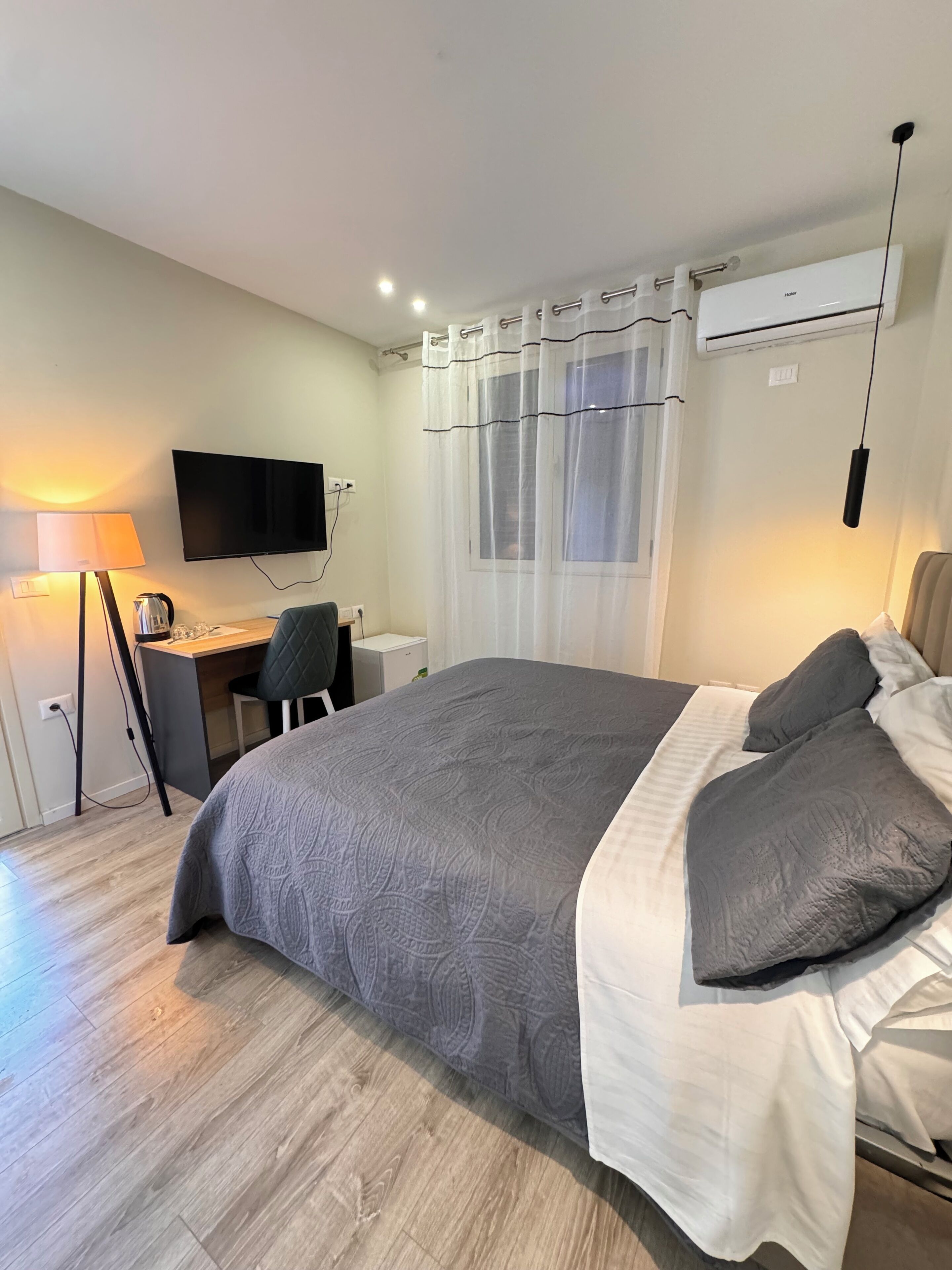 Une chambre d’hôtel moderne équipée d’un grand lit, d’un bureau, d’une chaise, d’un téléviseur à écran plat et d’un système de climatisation.