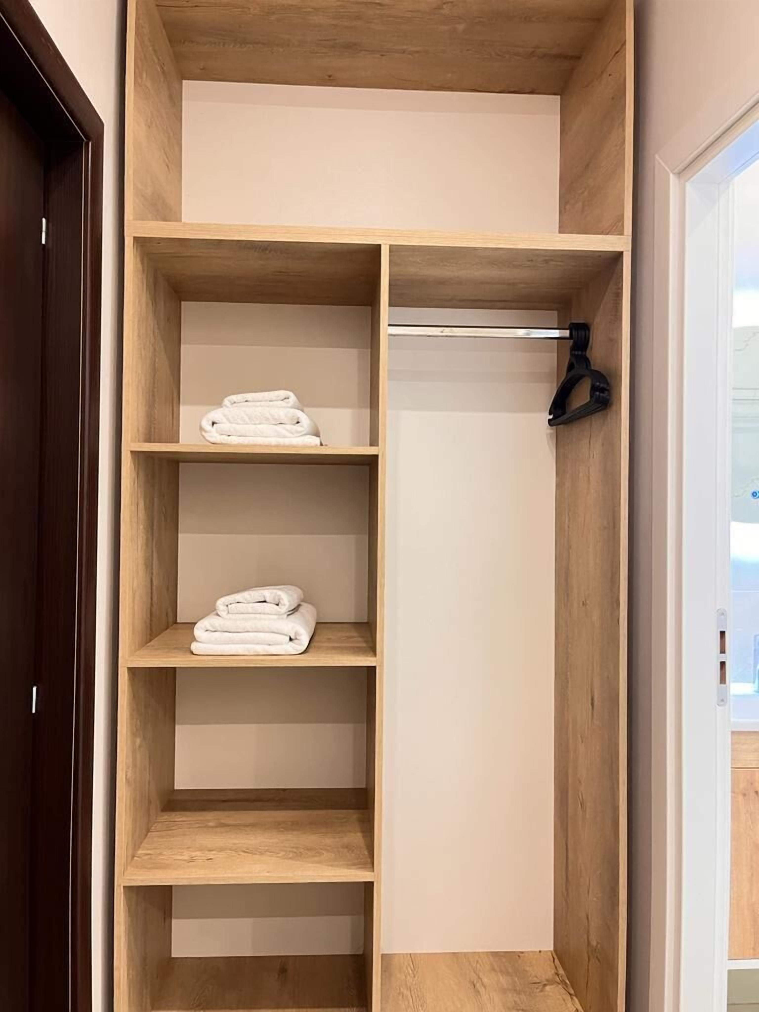 A wooden closet with multiple shelves, some holding folded towels.
