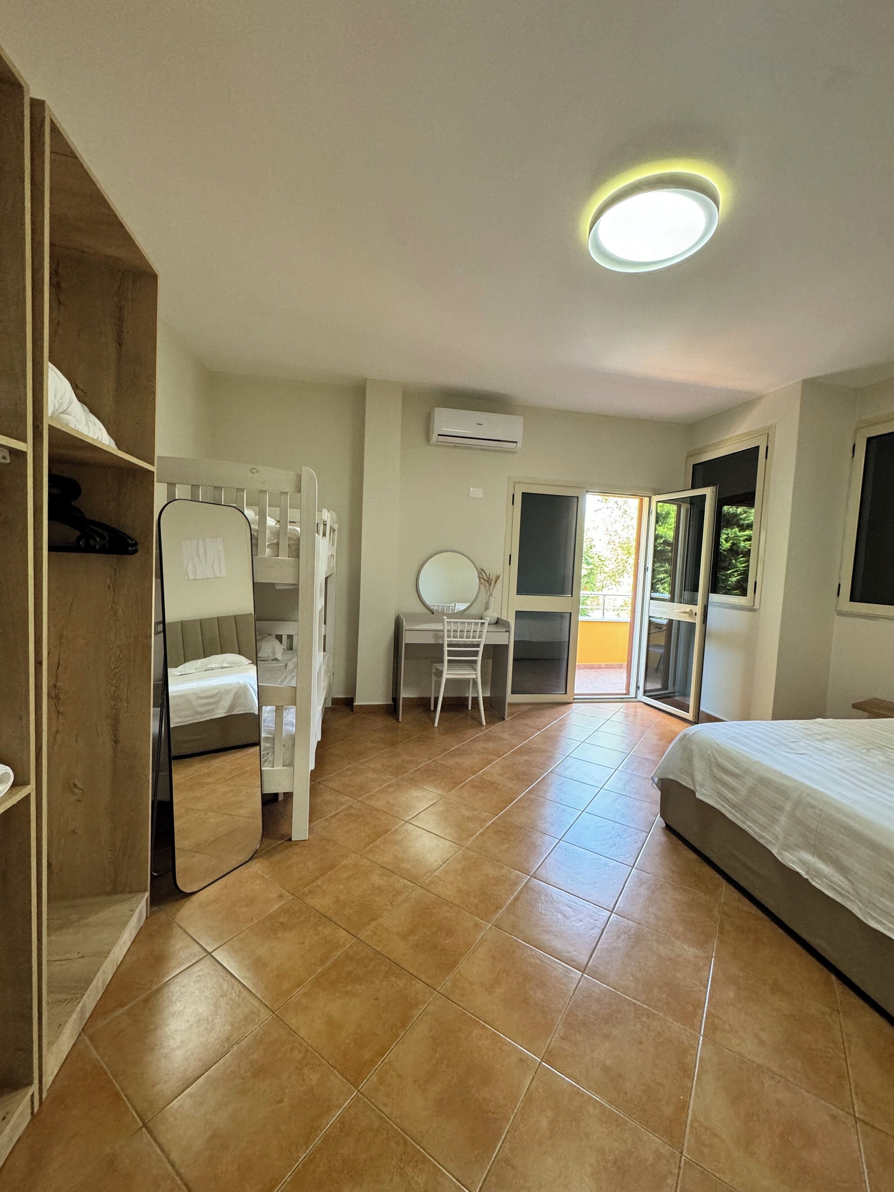 Une chambre à coucher comprenant un lit, un bureau avec une chaise, une armoire et une porte-fenêtre coulissante donnant sur un espace extérieur.