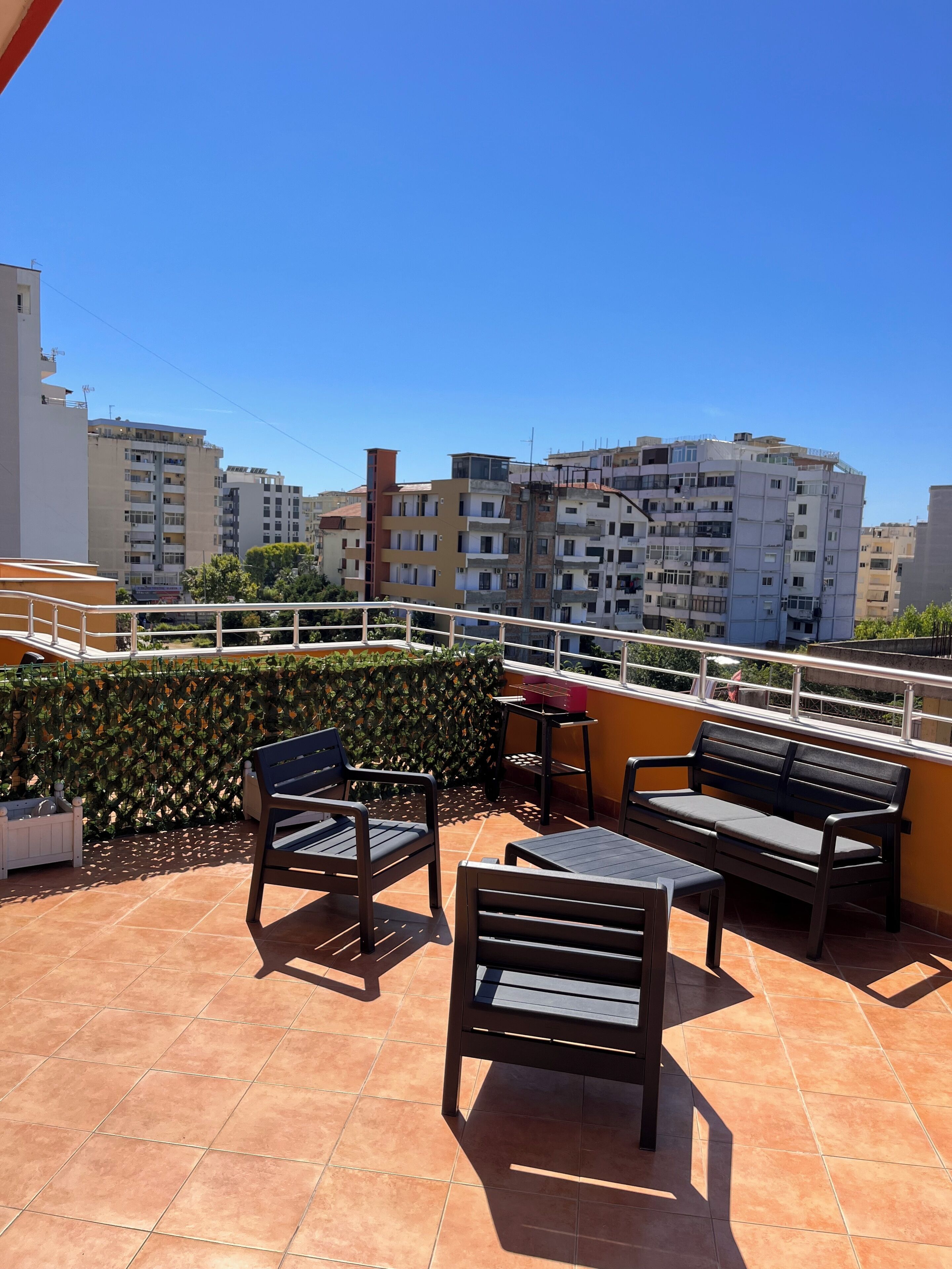 A terrace with outdoor furniture, a tiled floor, and a view of surrounding buildings.