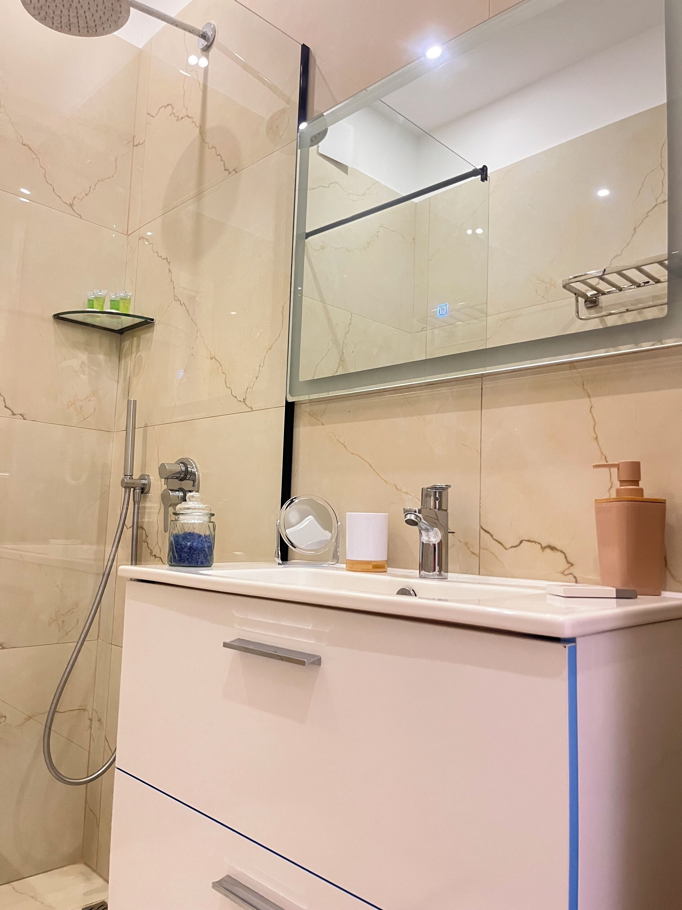 A modern bathroom with a glass shower enclosure, a vanity with a mirror, and a sink.