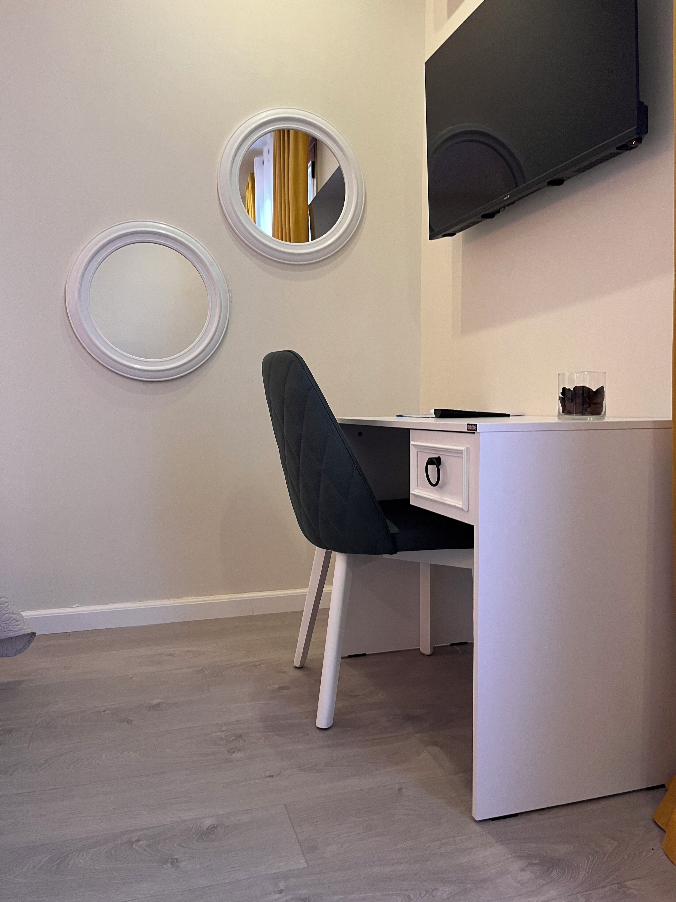 A modern office space with a desk, chair, and two wall-mounted mirrors.