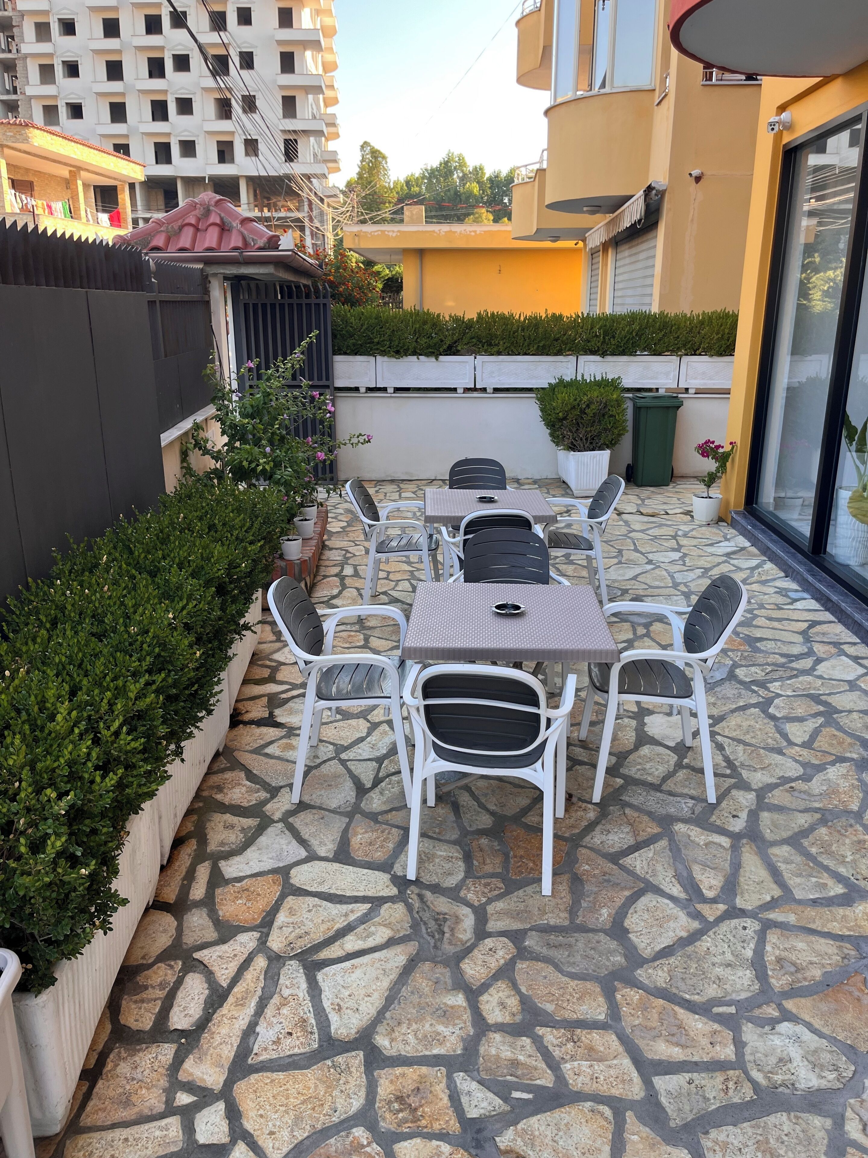 A patio with stone flooring, white metal chairs, and a table.