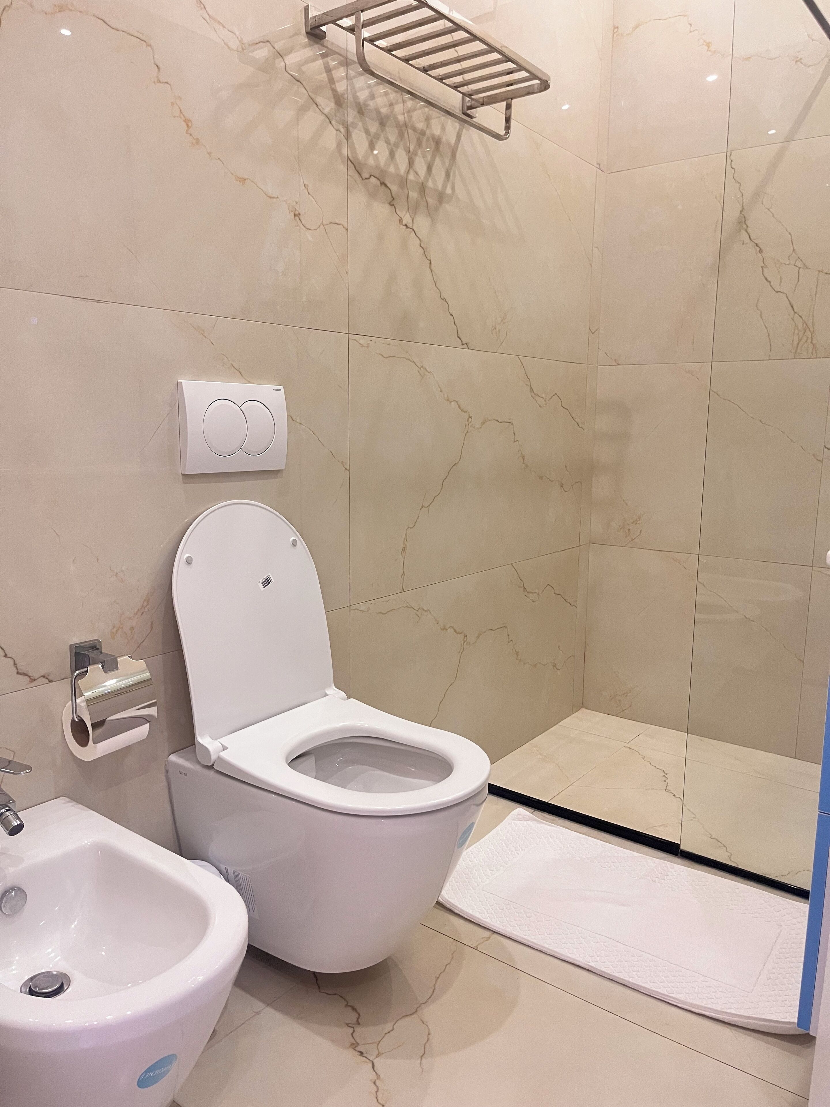 A modern bathroom with a toilet, bidet, and a glass shower enclosure.