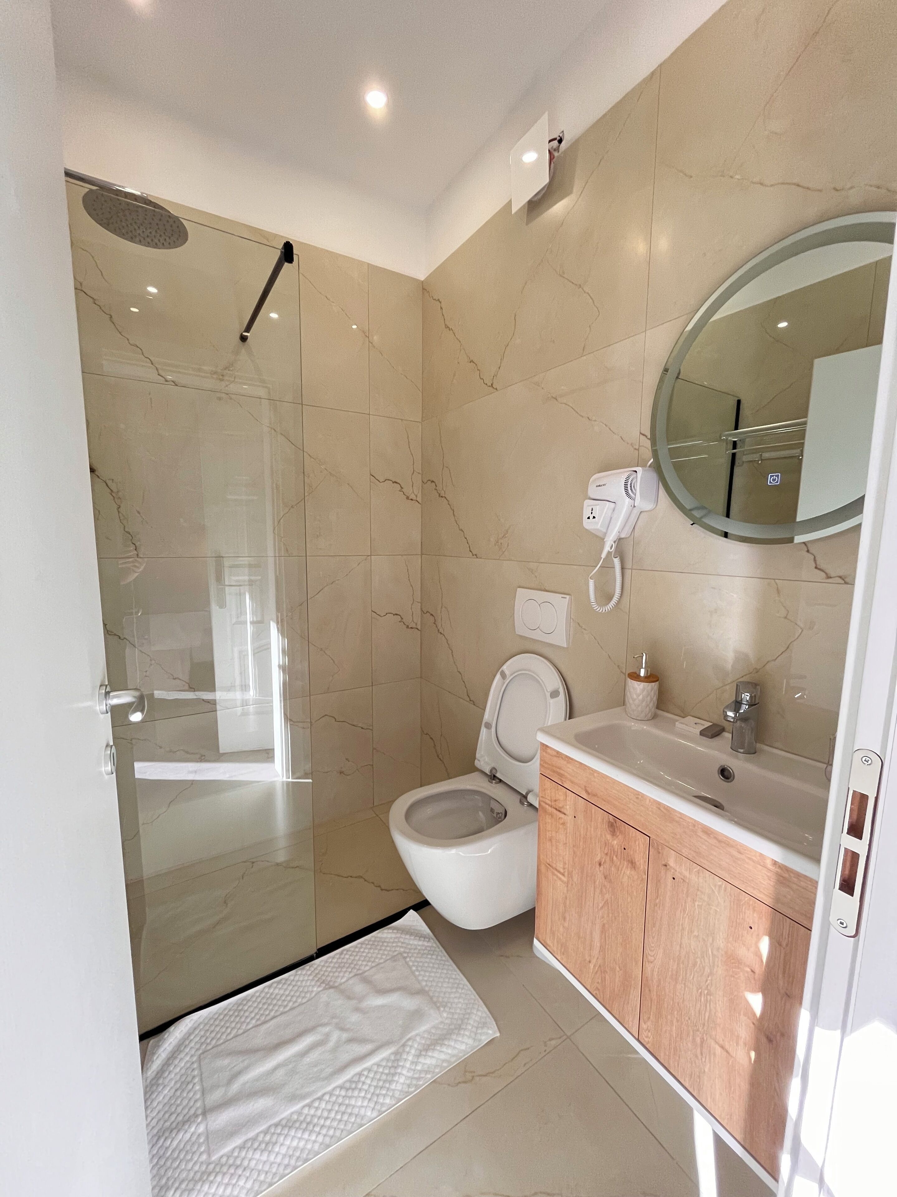 Een moderne badkamer met een douchecabine van glas, een toilet en een wastafel met spiegel.