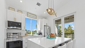 A modern kitchen with white cabinetry, stainless steel appliances, and a large island with bar stools.
